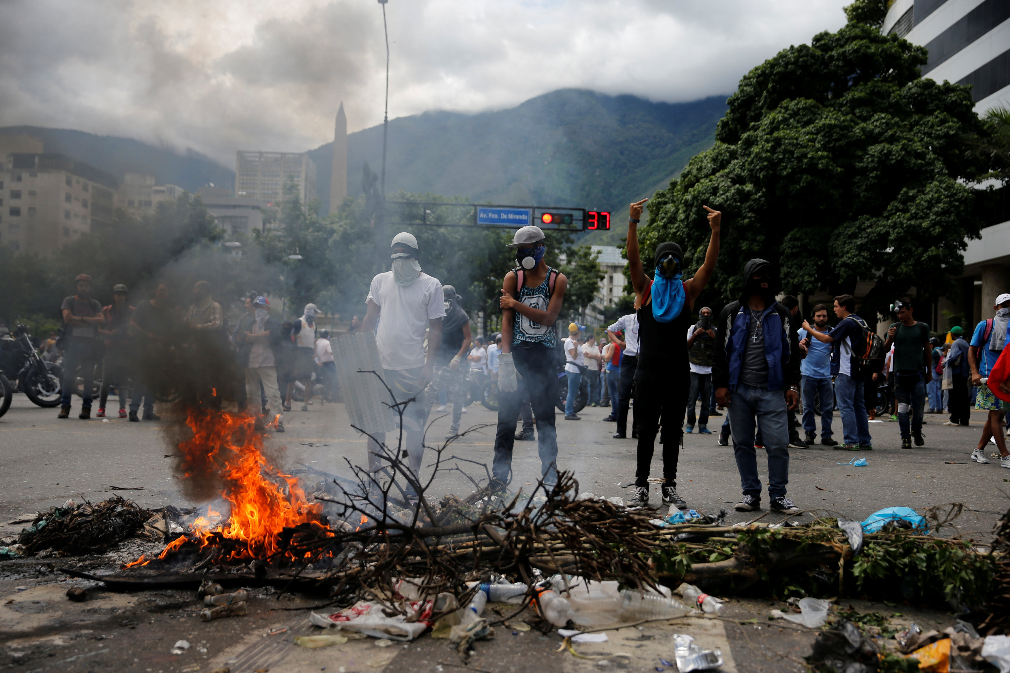 Protesters stand behind a burning barricade during a rally against Venezuela's President Nicolas Maduro's government in Caracas - TMPOUT